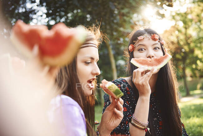 Giovani donne boho fare faccina sorridente con fetta di melone al festival — Foto stock