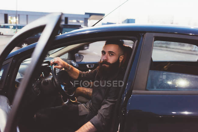 Barbudo hombre en coche mirando a la cámara - foto de stock