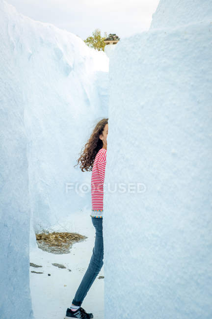 Menina caminhando atrás da parede branca, Santorini, Kikladhes, Grécia — Fotografia de Stock