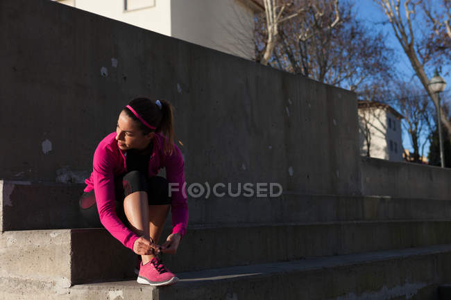 Молода жінка зав'язує шнурки на тренувальному взутті — стокове фото