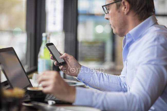 Uomo in caffetteria con smartphone — Foto stock