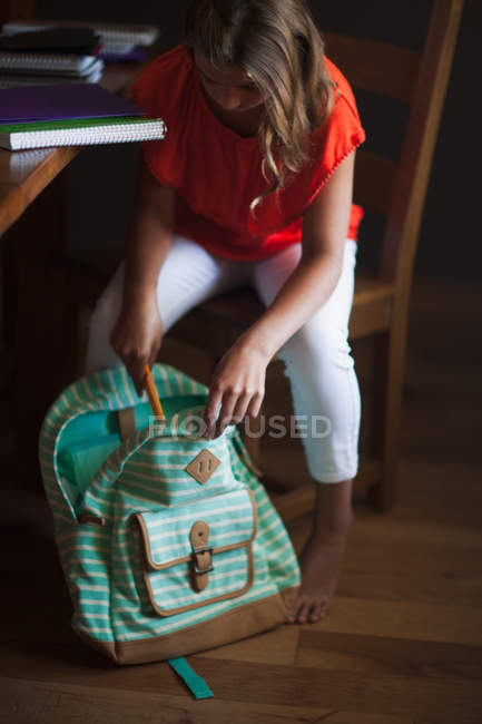 Menina mochila de embalagem com material de papelaria escolar — Fotografia de Stock