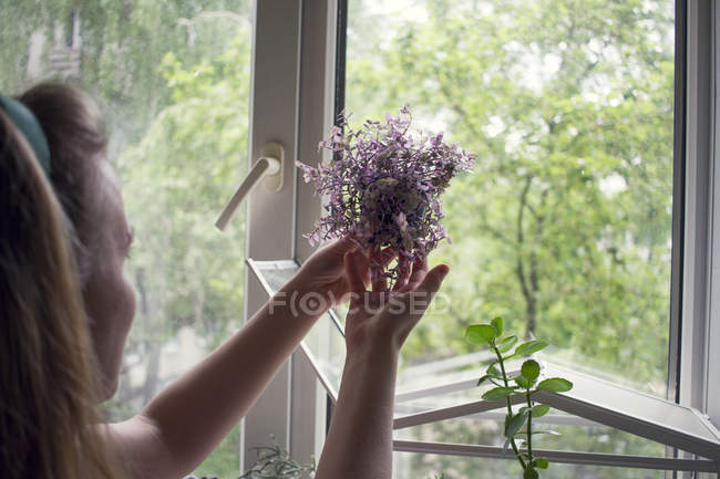 Over shoulder view of woman holding  and looking at potted plant — Stock Photo