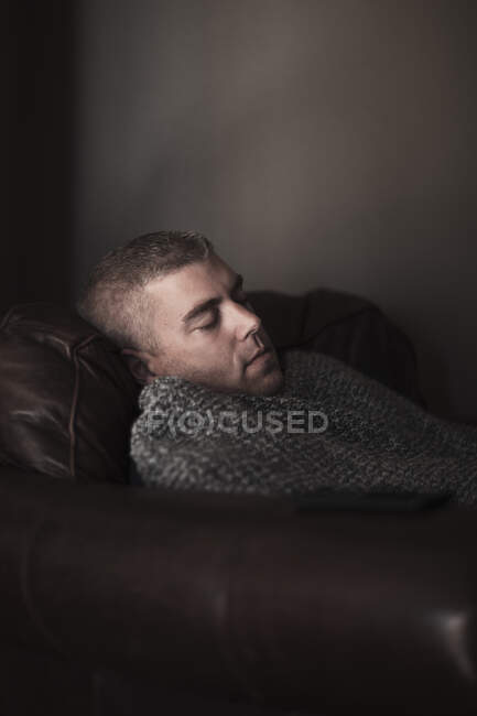 Hombre maduro envuelto en manta dormido en sillón - foto de stock