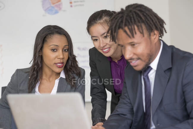 Empresarios y mujeres de negocios, en la oficina, lluvia de ideas, utilizando el ordenador portátil - foto de stock