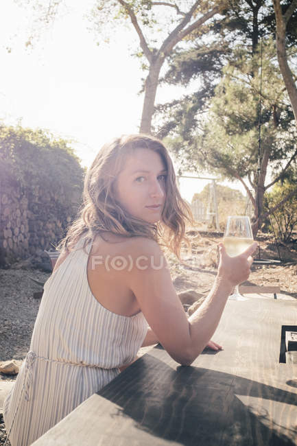 Portrait of young woman sitting outdoors with wine glass — Stock Photo