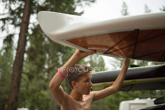 Teenage boy retrieving surfboard from car — Stock Photo