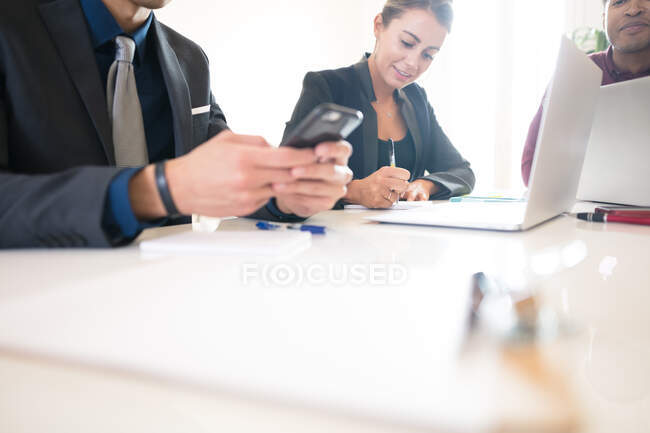 Снимок бизнесмена, смотрящего на смартфон во время встречи — стоковое фото