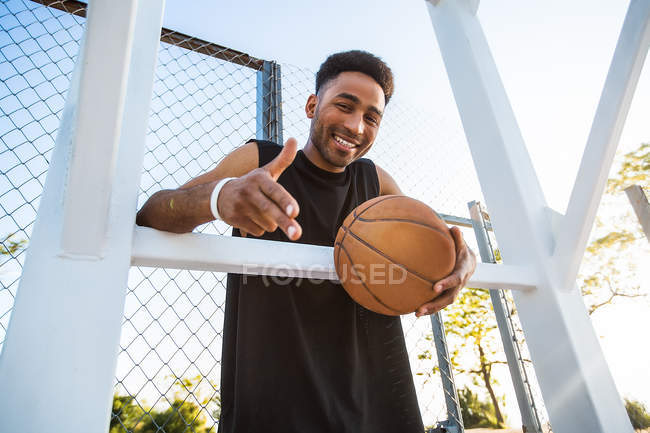 Porträt eines lächelnden jungen Mannes mit Basketballkorb — Stockfoto
