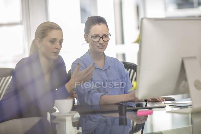 Две молодые офисные работницы встречаются за столом — стоковое фото