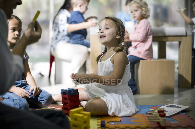Вчитель і діти граються з будівельними блоками — стокове фото