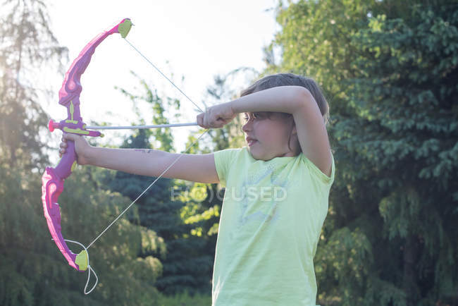 Молодая девушка играет с луком и стрелами — стоковое фото