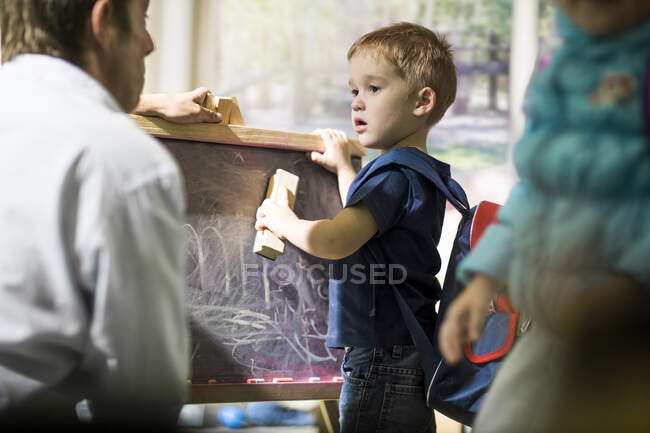 Menino de limpeza blackboard com espanador — Fotografia de Stock