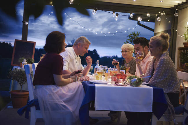 Grupo de pessoas ao ar livre, sentado à mesa, desfrutando de refeição — Fotografia de Stock