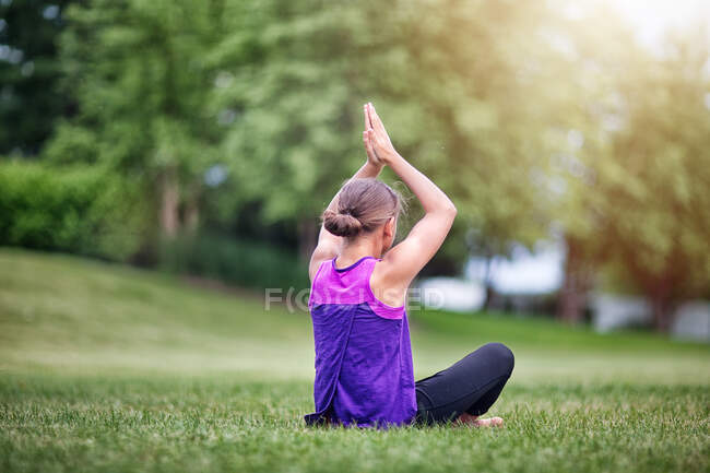 Girl in yoga pose on grass — Stock Photo