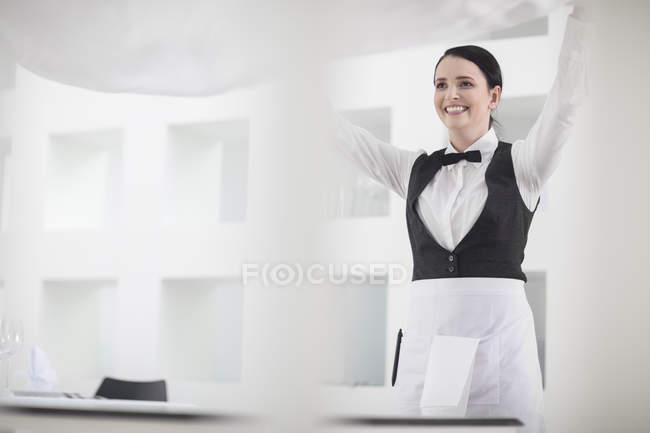 Kellnerin im Restaurant deckt Tischdecke — Stockfoto