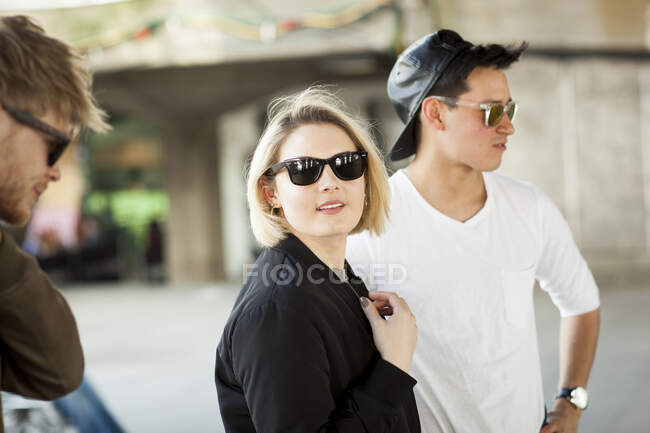 Три друга на улице, молодая женщина смотрит в камеру — стоковое фото