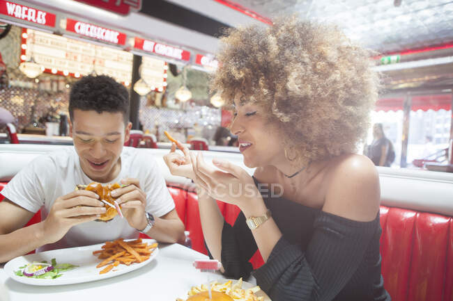Casal jovem, sentado no restaurante, comendo refeição — Fotografia de Stock