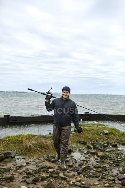 Retrato de pescador macho joven con caña de pescar - foto de stock