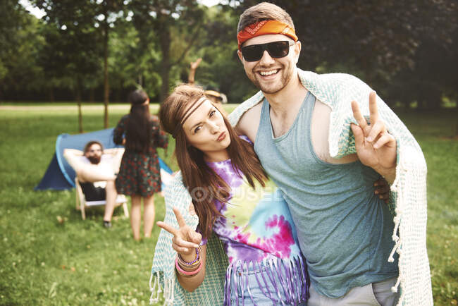Portrait of young boho couple making peace signs at festival — Stock Photo