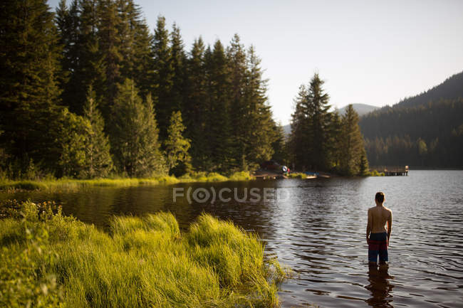 Visão traseira do adolescente de pé no lago — Fotografia de Stock