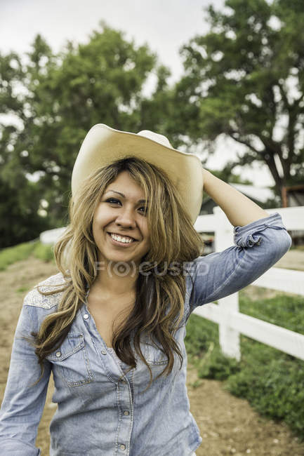 Portrait de jeune femme en plein air, vêtue d'un chapeau de cow-boy, souriante — Photo de stock