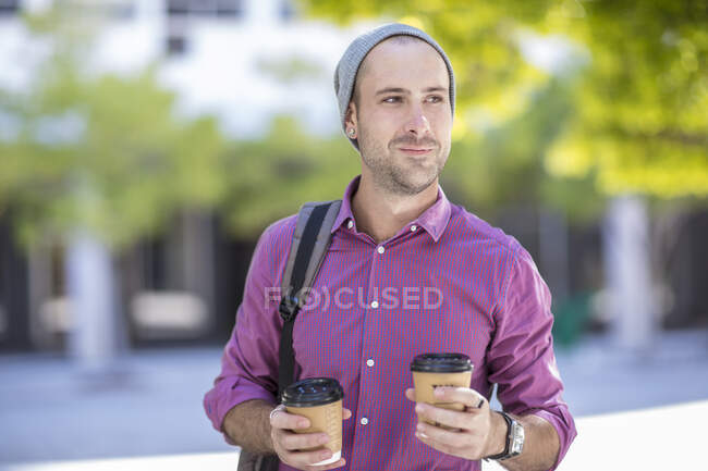Jovem ao ar livre, segurando dois taças de café takeaway — Fotografia de Stock