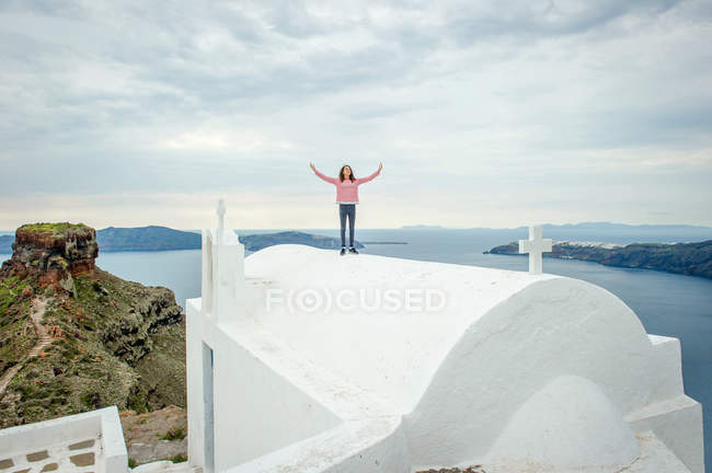 Chica de pie en la cima de la iglesia, Santorini, Kikladhes, Grecia - foto de stock