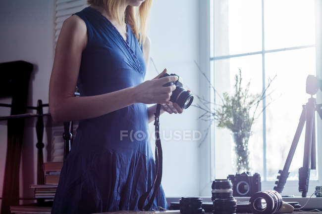 Donna che tiene la fotocamera vicino alla finestra — Foto stock