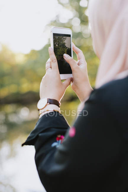 Молода жінка фотографується на смартфоні — стокове фото