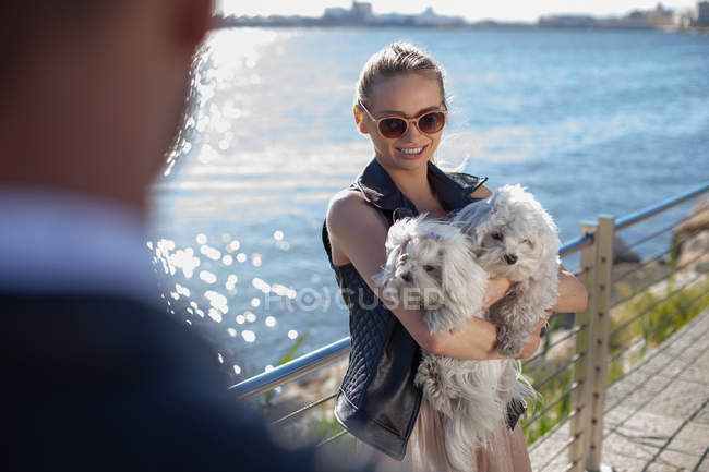 Mujer sosteniendo perros en el paseo marítimo, Cagliari, Cerdeña, Italia, Europa - foto de stock