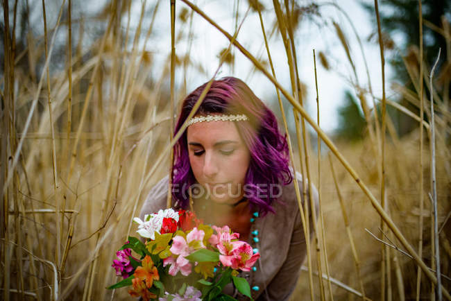 Portrait of Woman with bouquet of flowers among tall grass — Stock Photo