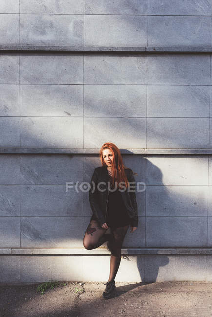 Portrait of red haired woman leaning against wall — Stock Photo