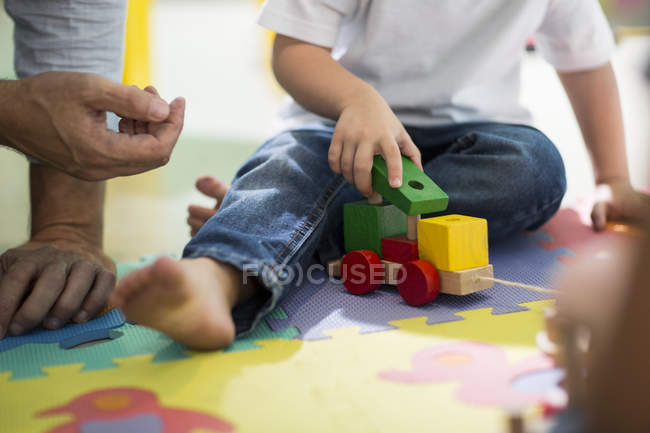 Учитель и мальчик играют с игрушечным поездом — стоковое фото