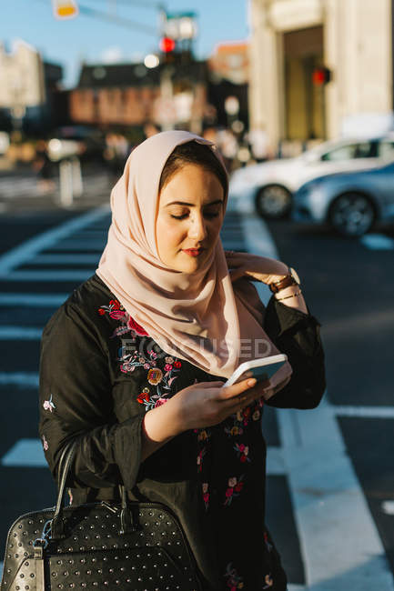 Junge Frau im Hidschab schaut im Freien auf Smartphone — Stockfoto