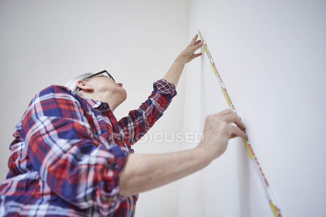 Женщина измеряет белую стену — стоковое фото