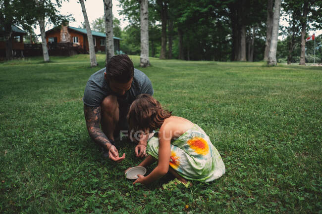 Father and daughter outdoors, crouching, collecting berries — Stock Photo