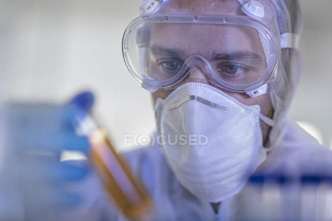 Лабораторний працівник, що тримає рідку заповнену пробірку, крупним планом — стокове фото