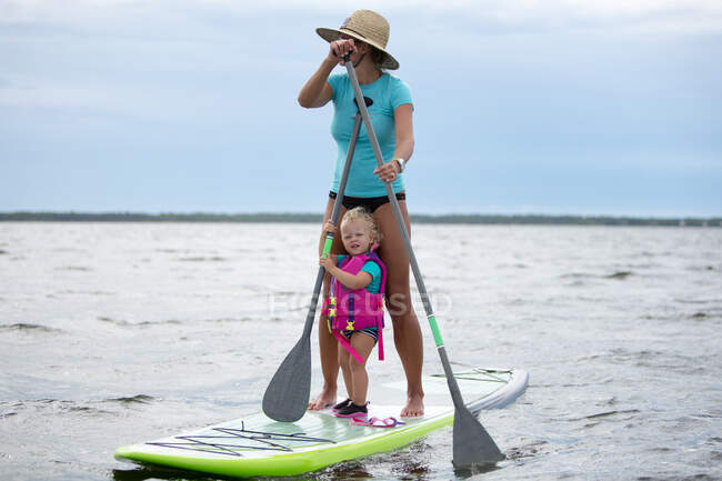 Madre e hija joven en el tablero de paddle - foto de stock