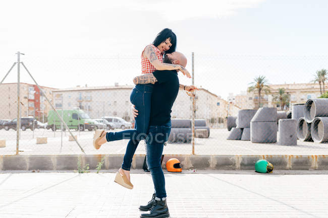 Зрілий хіпстер піднімає і обіймає дівчину в місті — стокове фото