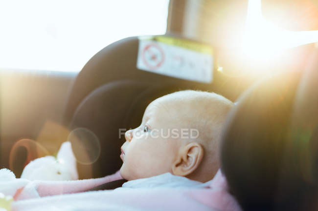 Vista lateral del pequeño bebé en el asiento del coche - foto de stock
