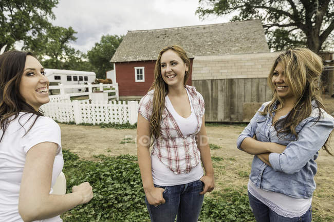 Three women standing together on farm, talking, smiling — Stock Photo