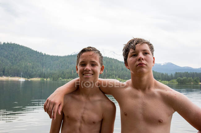 Portrait of two teenage brothers beside water — Stock Photo