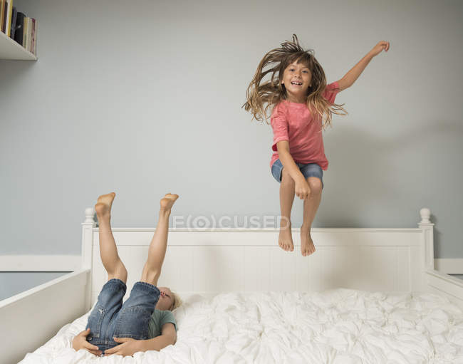 Mädchen in der Luft springt auf Bett im Schlafzimmer — Stockfoto