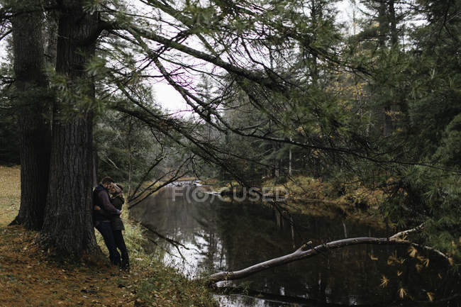 Coppia abbracci vicino all'albero accanto al fiume, Bancroft, Canada, Nord America — Foto stock