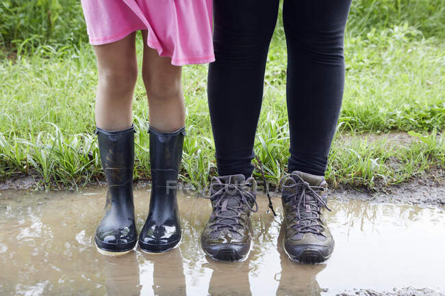 Two girls standing in mud, low section — Stock Photo