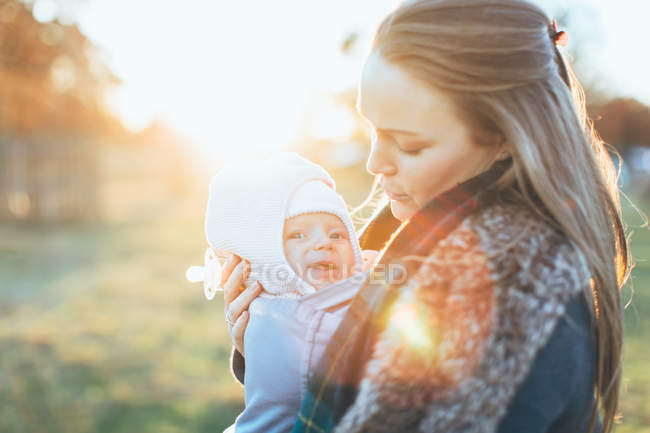 Side view of Mother and baby daughter outdoors, mother carrying baby in baby sling — Stock Photo