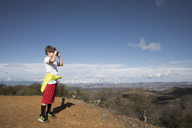 Boy exploring with camera in hills, Thousand Oaks, California, US — Stock Photo