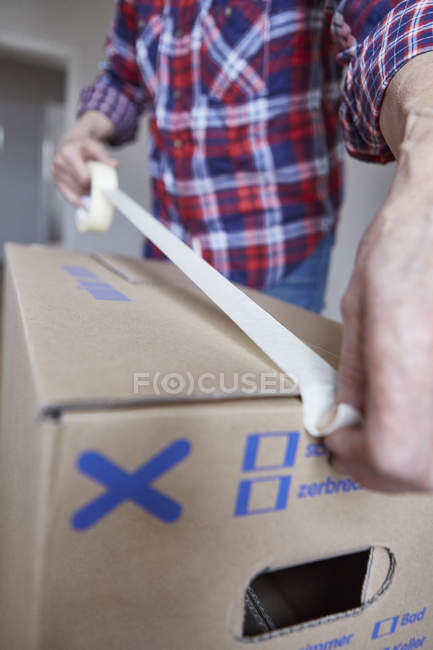 Person sealing box with masking tape — Stock Photo