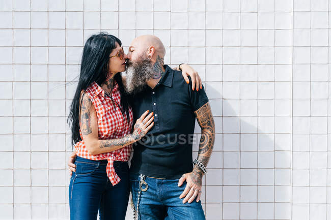 Maduro hipster casal beijos na frente de branco parede — Fotografia de Stock